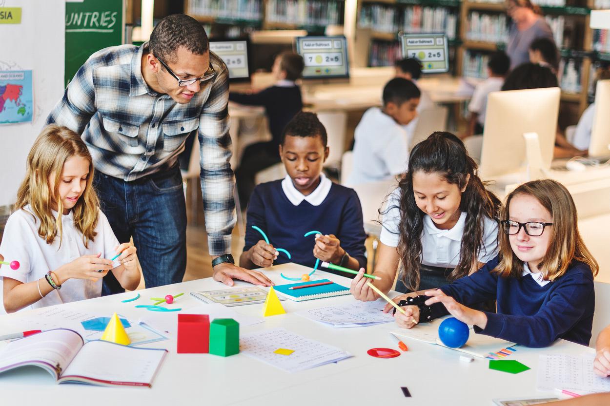 children engaged in hands-on learning with a teacher during a math activity