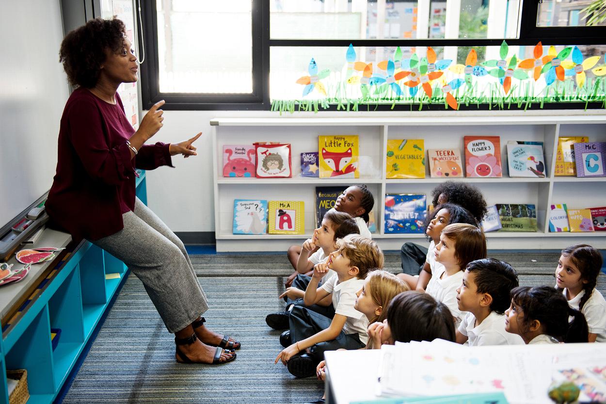 teacher engaging with children in a classroom surrounded by colorful books