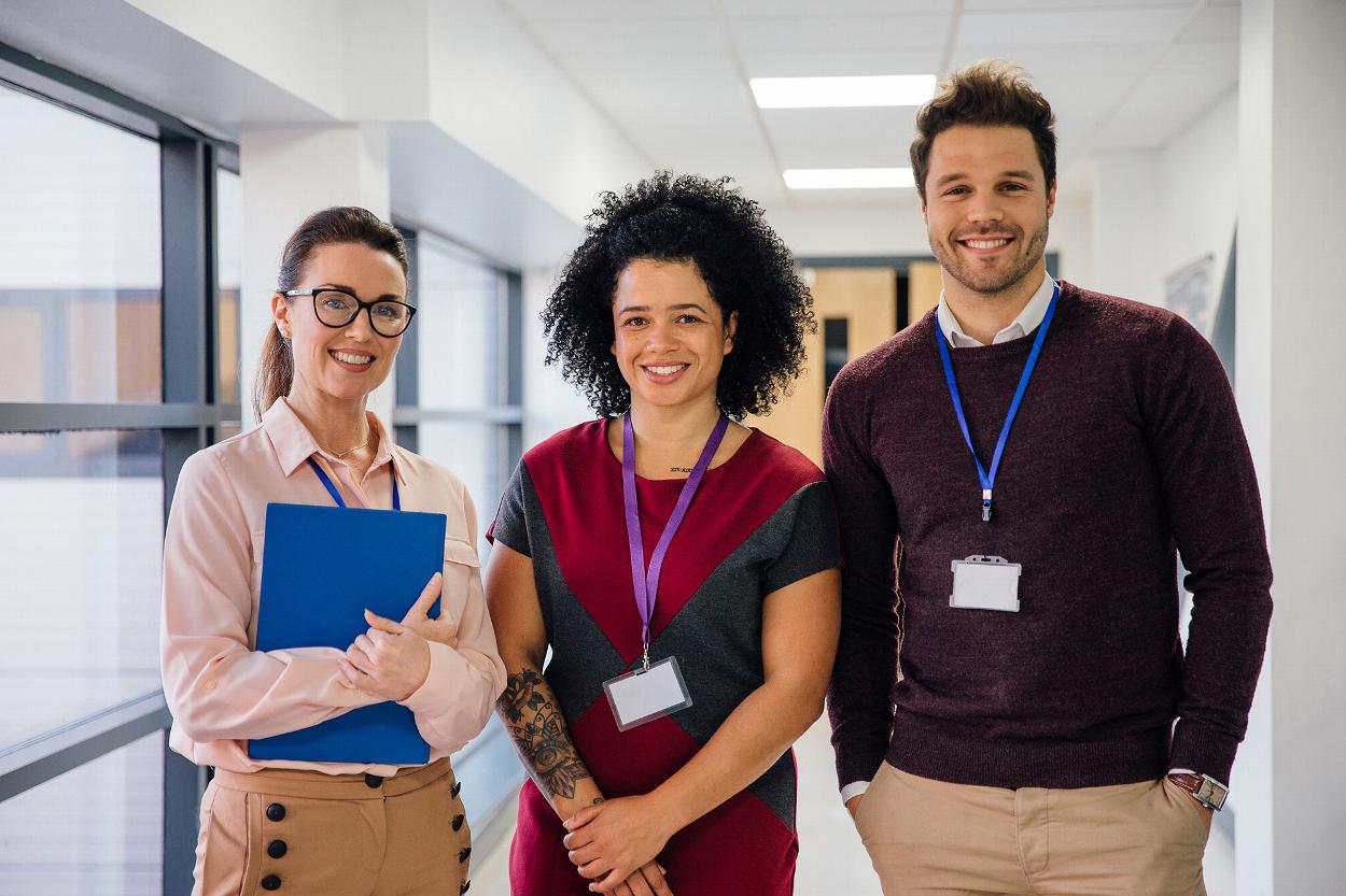 three diverse professionals smiling together in a modern office